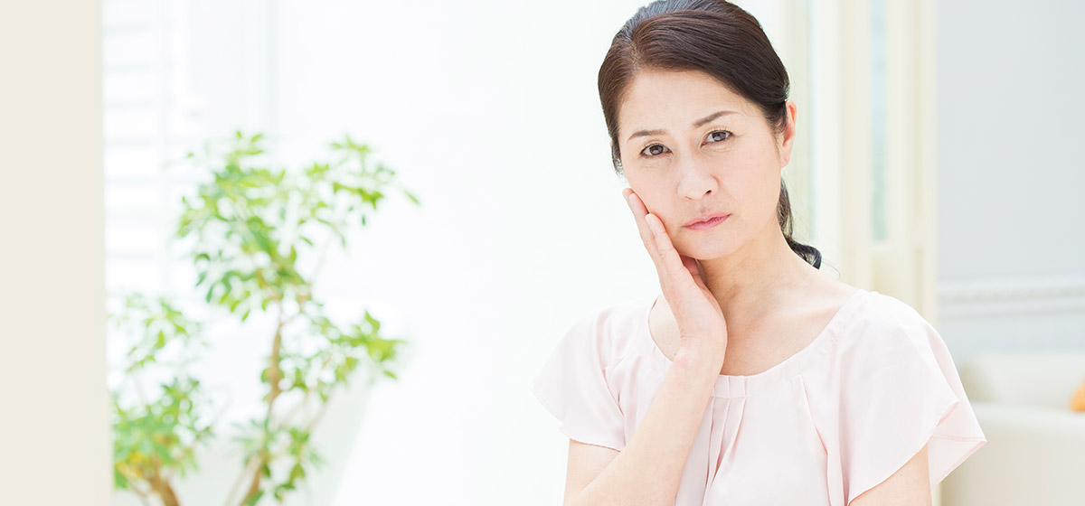 頬をおさえる女性